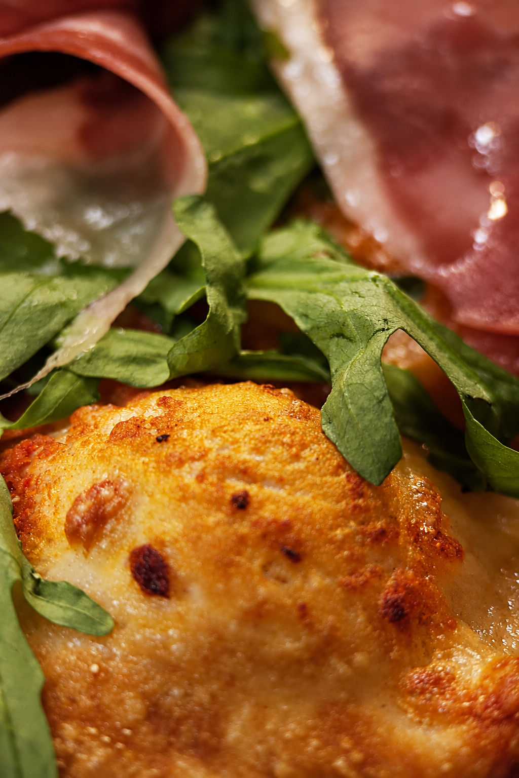Close-up Italian pizza food photography with prosciutto and rocket at RA-FT Café