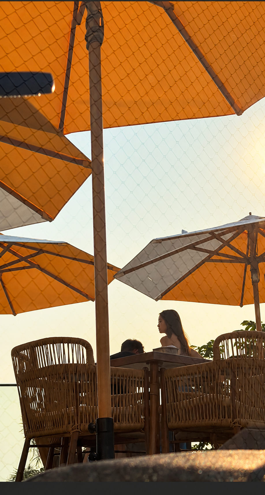 A guest seated beneath orange parasols at MUSE Peranakan Bistro By The Sea in Melaka.
