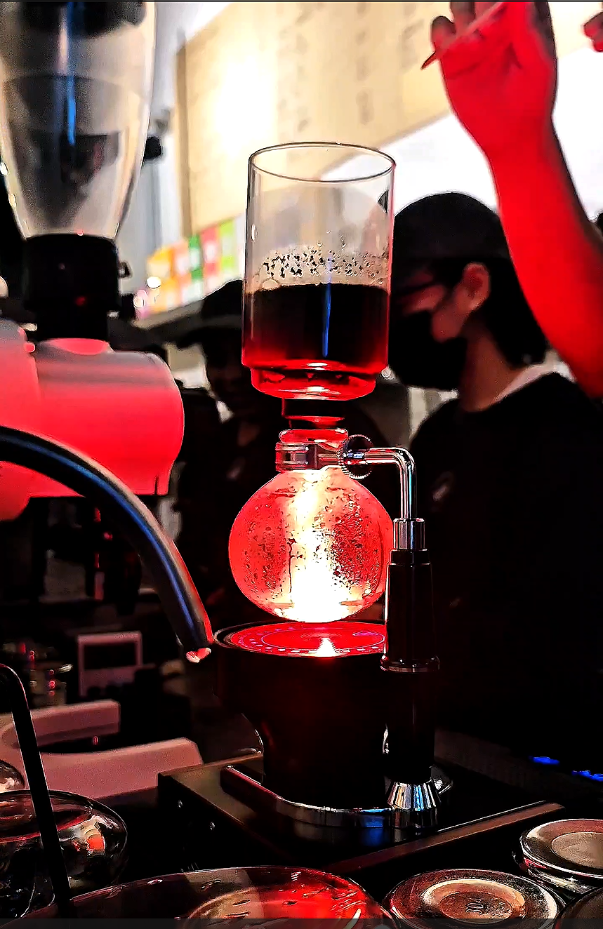 Siphon coffee brewing equipment glowing during extraction at The Hidden Lab